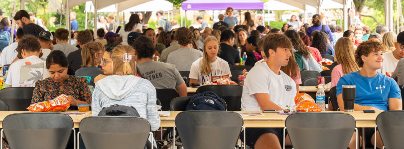 Students and staff gathered on Bosco Plaza eating lunch in rows of tables and chairs